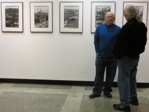 David Akiba and a guest to the exhibit with Akiba's photographies in the background